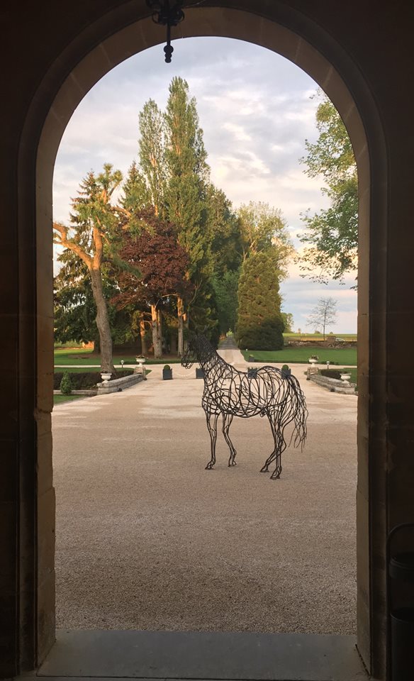 Le Château du Faucon vu à travers son arche d'entrée, avec la sculpture équestre en fil de fer