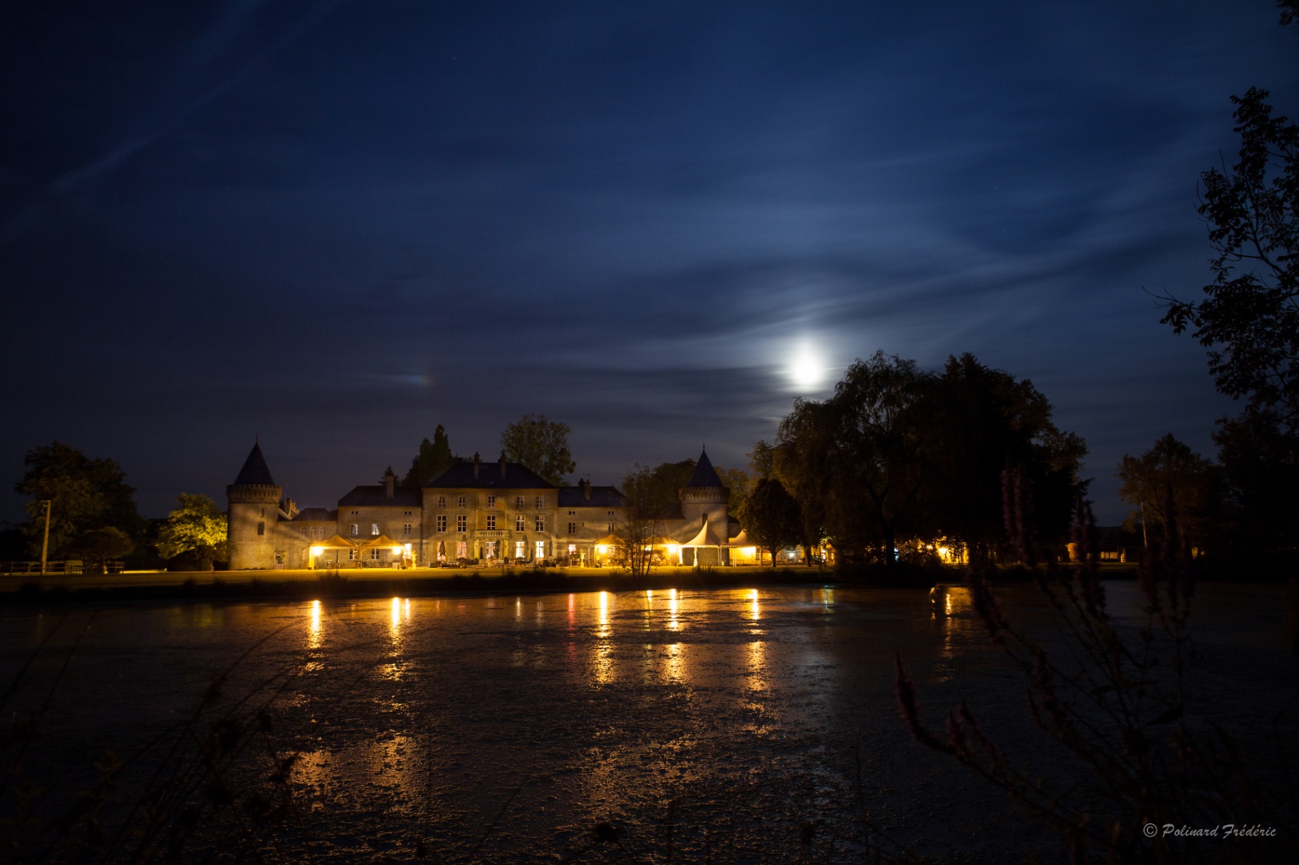 Château illuminé de nuit au bord de l'eau
