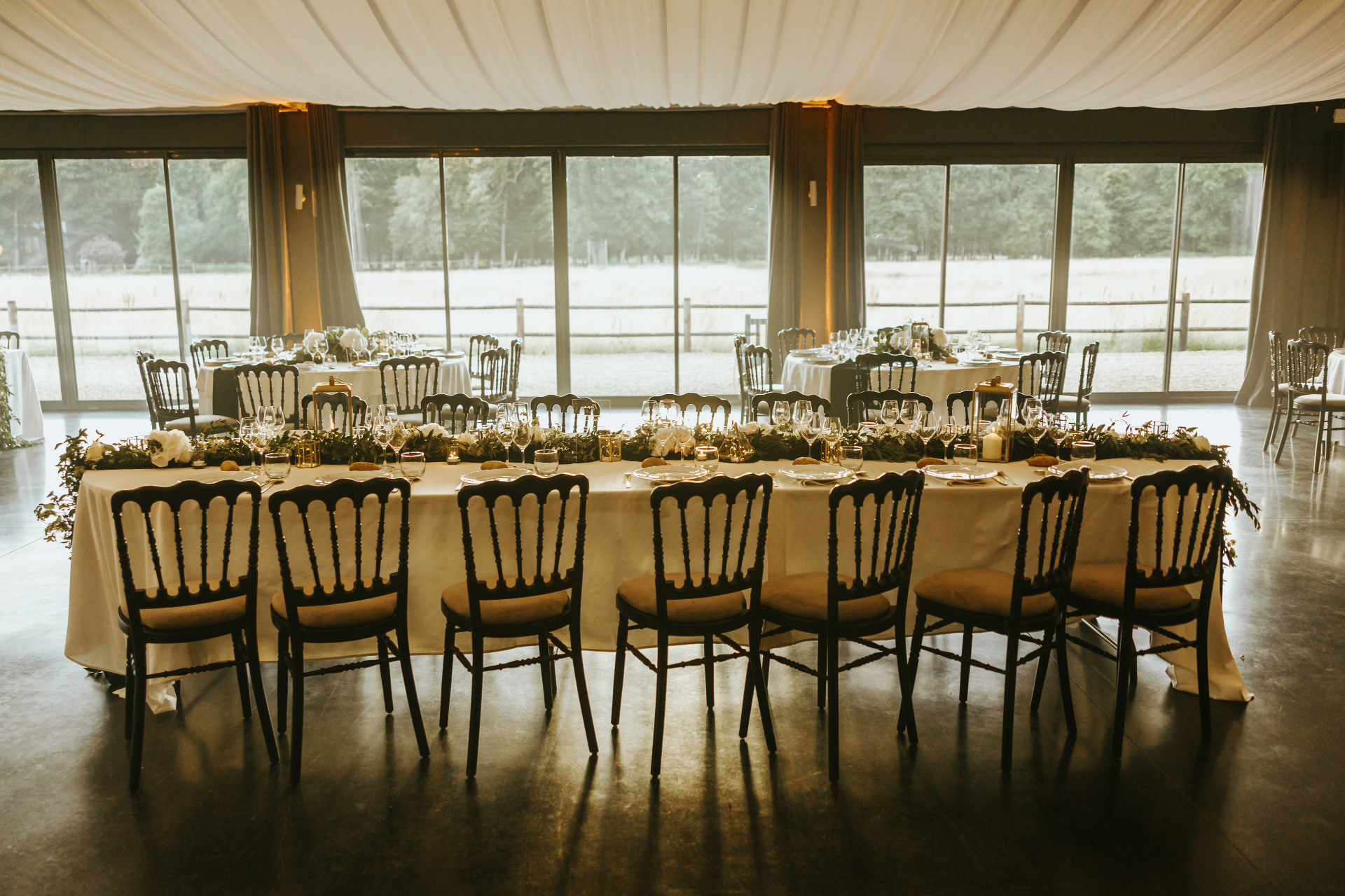Vue d'ensemble du salon champêtre avec grandes baies vitrées et tables de réception