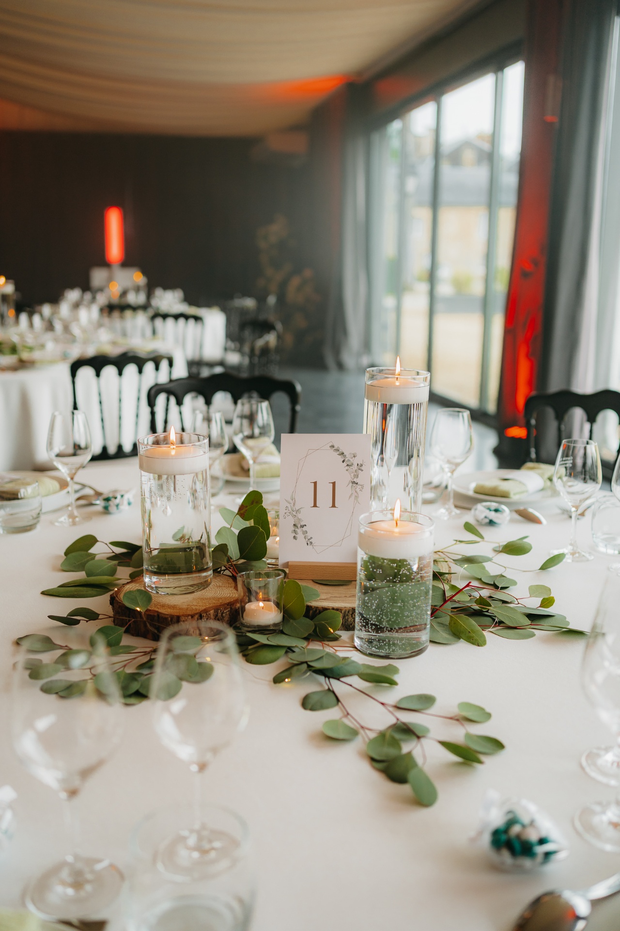 Table de mariage dressée dans le salon champêtre avec bougies flottantes et eucalyptus