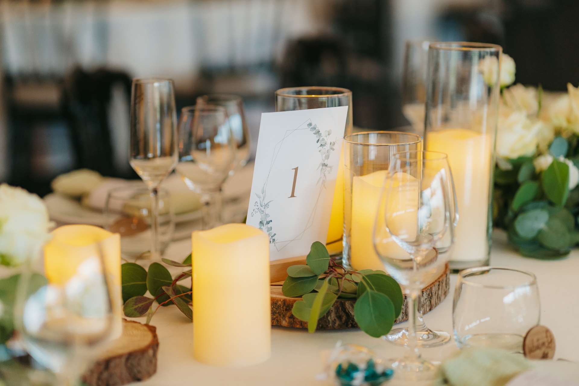 Centre de table avec bougies, rondins de bois et eucalyptus dans le salon champêtre